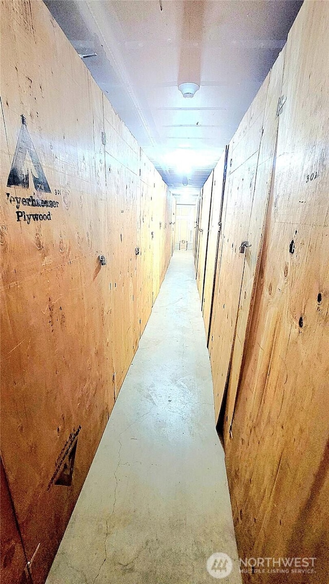 hallway with wood walls and unfinished concrete floors