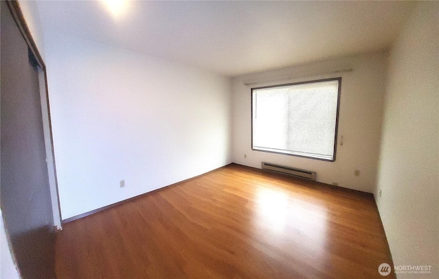 unfurnished bedroom featuring wood finished floors and baseboard heating