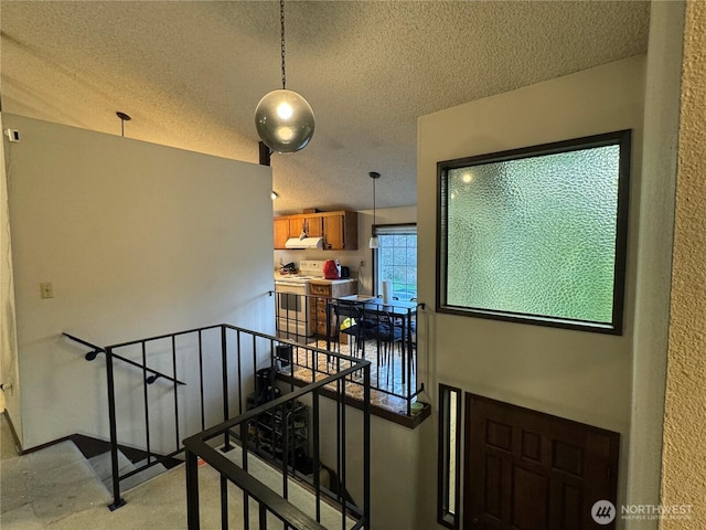 staircase with lofted ceiling and a textured ceiling