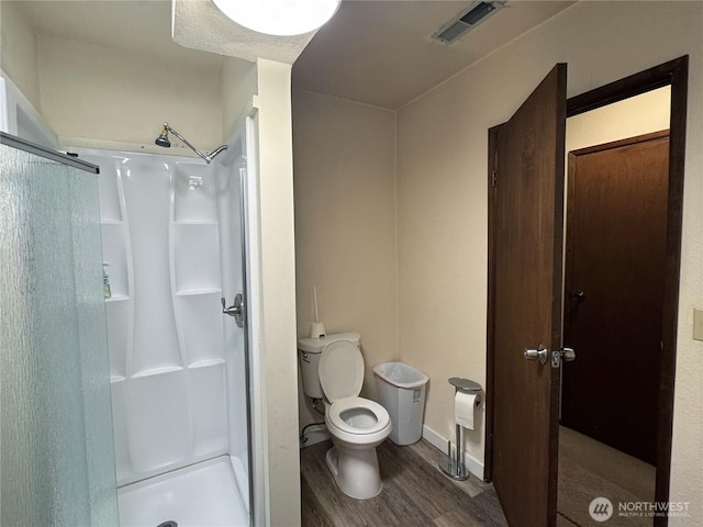 bathroom with visible vents, toilet, wood finished floors, and a shower stall