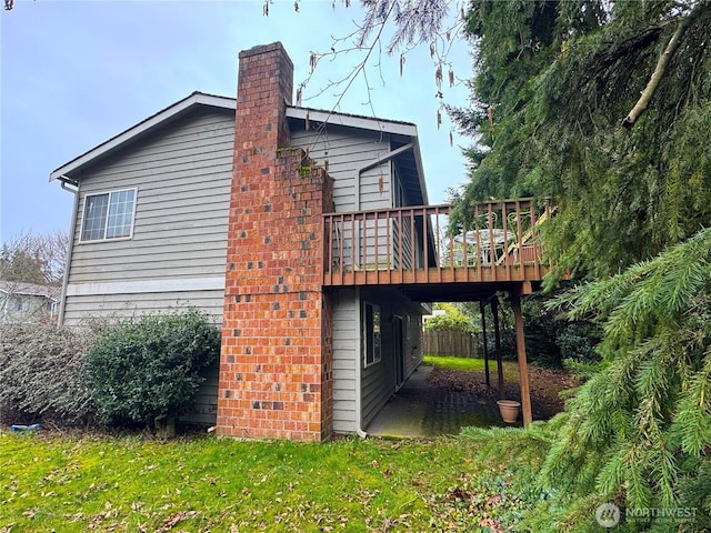 view of side of property with a lawn, a chimney, and a wooden deck