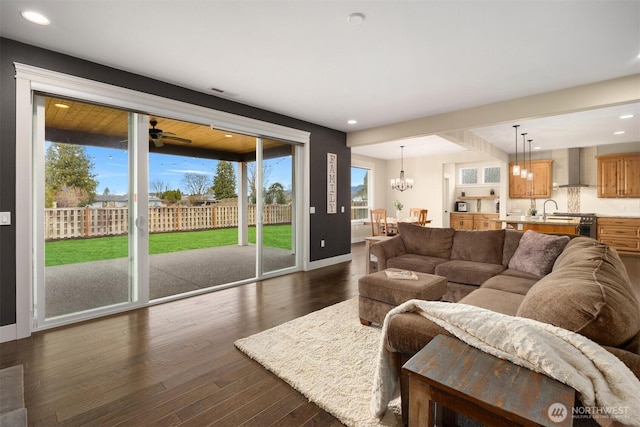 living room featuring recessed lighting, baseboards, dark wood finished floors, and ceiling fan with notable chandelier