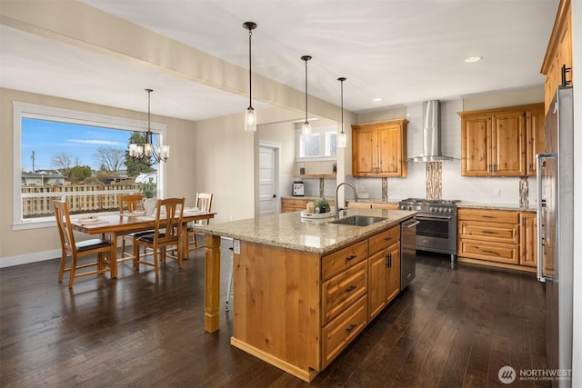 kitchen with a sink, dark wood finished floors, stainless steel appliances, wall chimney range hood, and light stone countertops