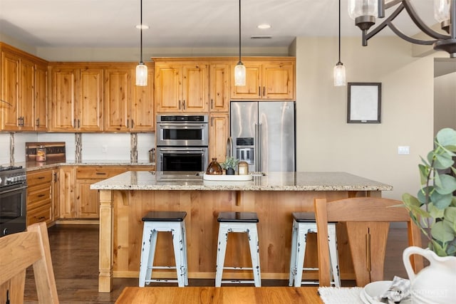 kitchen featuring backsplash, dark wood-type flooring, light stone countertops, appliances with stainless steel finishes, and a kitchen breakfast bar