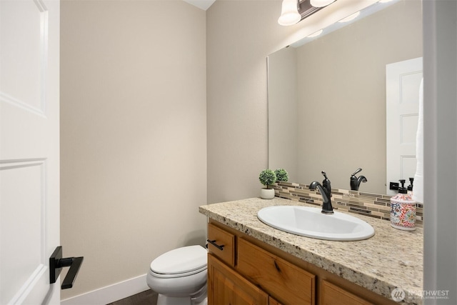 half bath featuring decorative backsplash, toilet, vanity, and baseboards