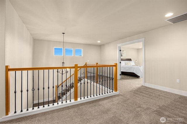 hallway with visible vents, carpet floors, baseboards, recessed lighting, and an upstairs landing