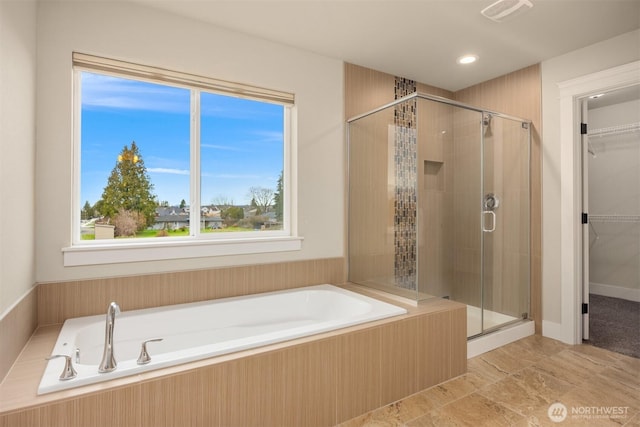 bathroom with a shower stall, a spacious closet, a garden tub, and visible vents