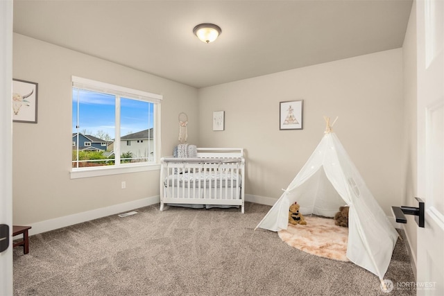 bedroom featuring a nursery area, baseboards, and carpet