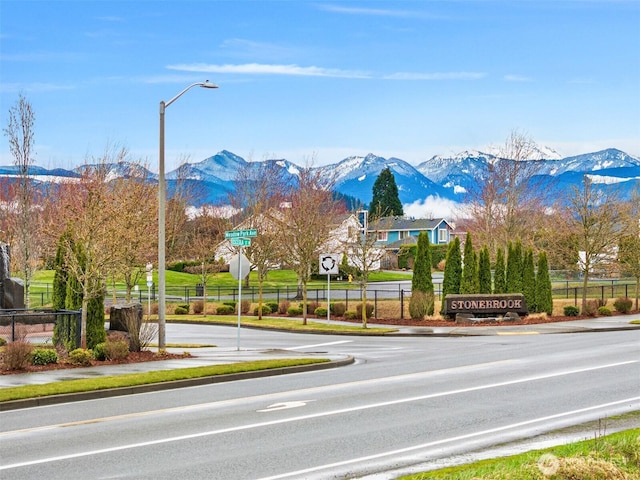 view of road featuring curbs, a mountain view, traffic signs, and sidewalks