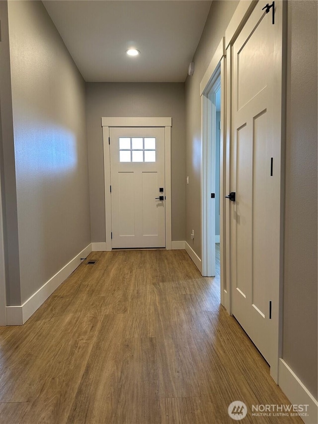 doorway featuring baseboards and wood finished floors