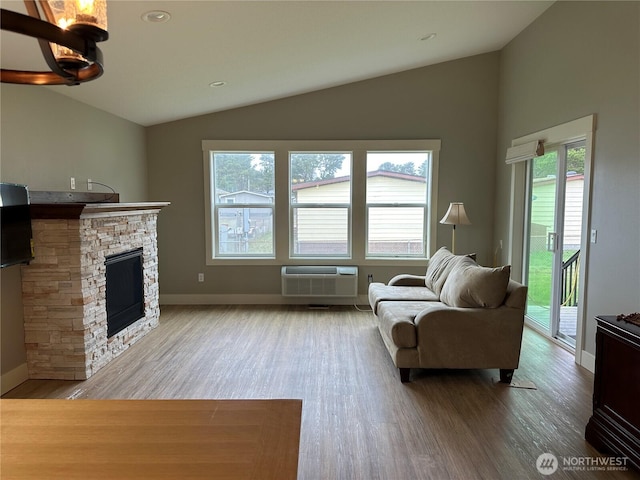 living area with lofted ceiling, a wall mounted AC, wood finished floors, a fireplace, and baseboards