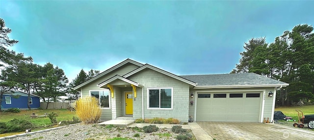 view of front of property featuring decorative driveway, fence, a garage, and a shingled roof