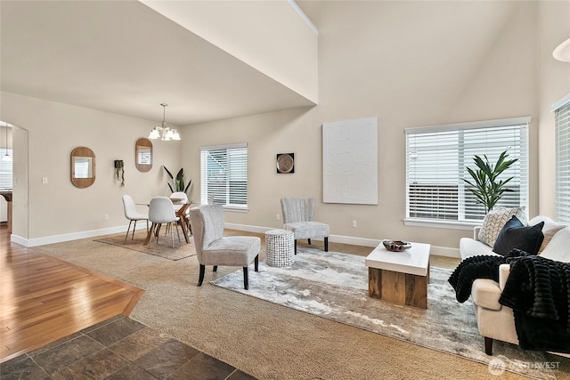 living room with a chandelier, a high ceiling, baseboards, and wood finished floors