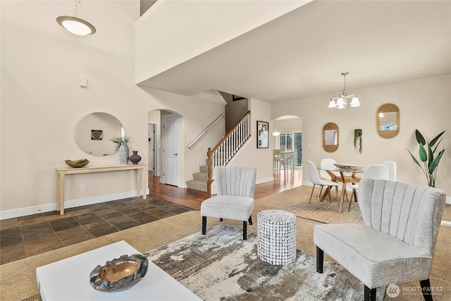 living room featuring stairway, baseboards, arched walkways, stone finish flooring, and a chandelier