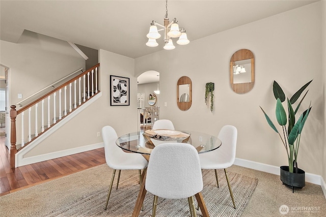 dining room with stairway, wood finished floors, baseboards, an inviting chandelier, and arched walkways