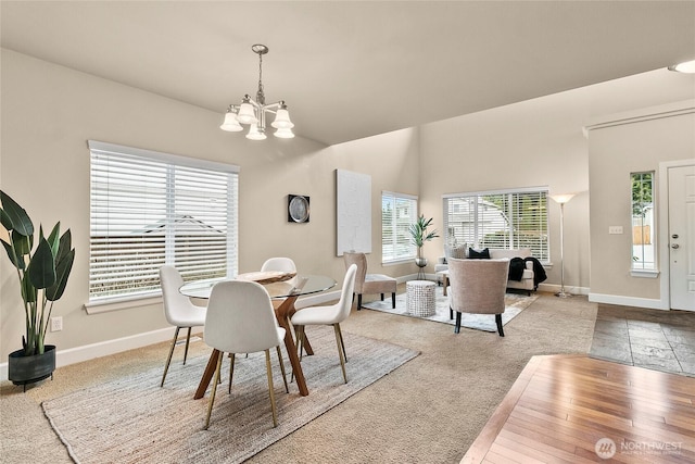 carpeted dining area featuring baseboards and a chandelier