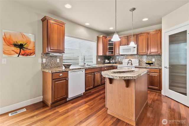 kitchen featuring white appliances, visible vents, dark wood finished floors, a sink, and tasteful backsplash