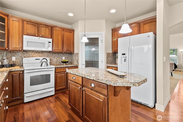 kitchen featuring brown cabinets, dark wood finished floors, white appliances, light countertops, and glass insert cabinets