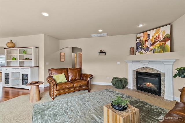 living area with baseboards, a fireplace, visible vents, and arched walkways