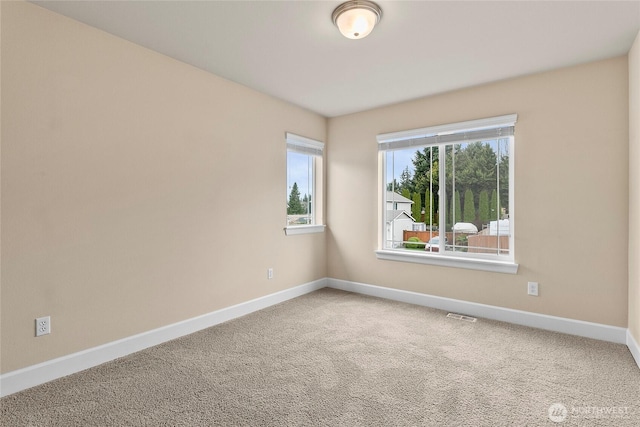 empty room featuring baseboards, visible vents, and carpet floors