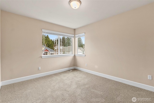 carpeted empty room featuring baseboards