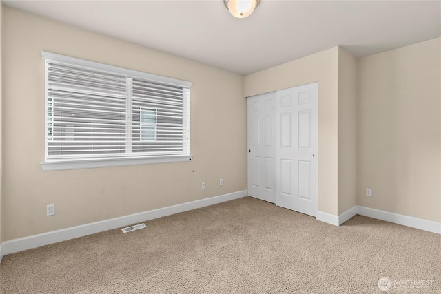 unfurnished bedroom featuring a closet, visible vents, baseboards, and carpet floors