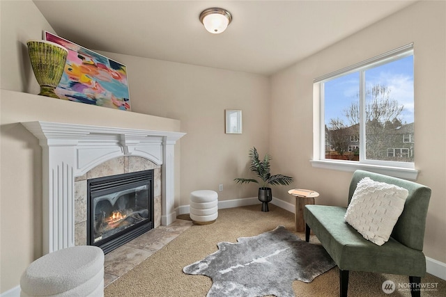 living area featuring a tiled fireplace and baseboards