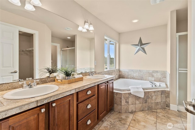 bathroom featuring double vanity, a stall shower, a garden tub, and a sink