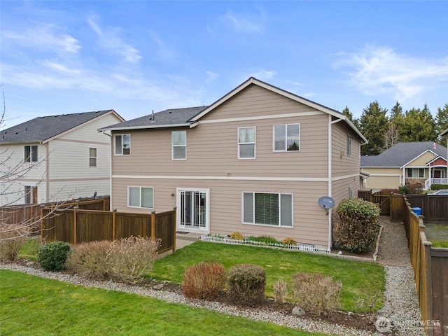 rear view of house featuring a yard and a fenced backyard