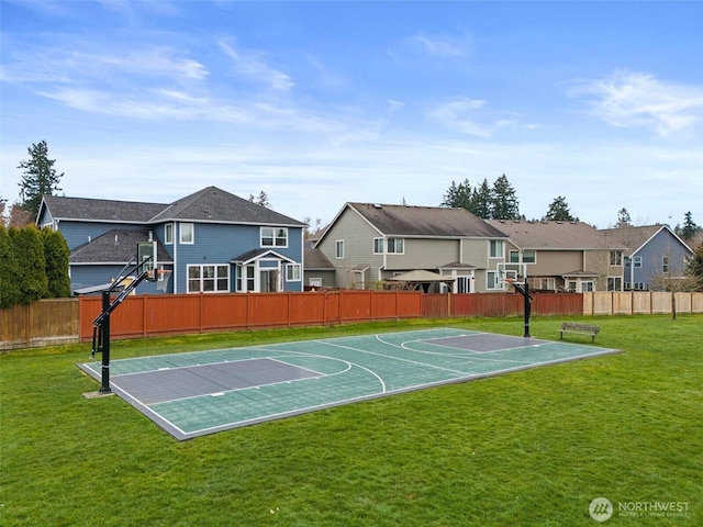 view of sport court with a residential view, a lawn, basketball hoop, and fence