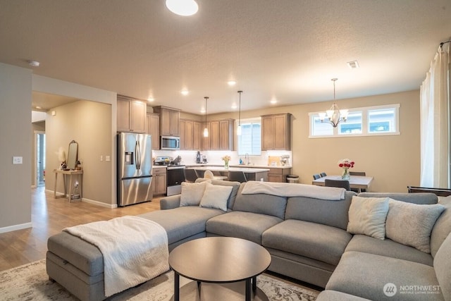 living area featuring visible vents, recessed lighting, light wood-style floors, an inviting chandelier, and baseboards