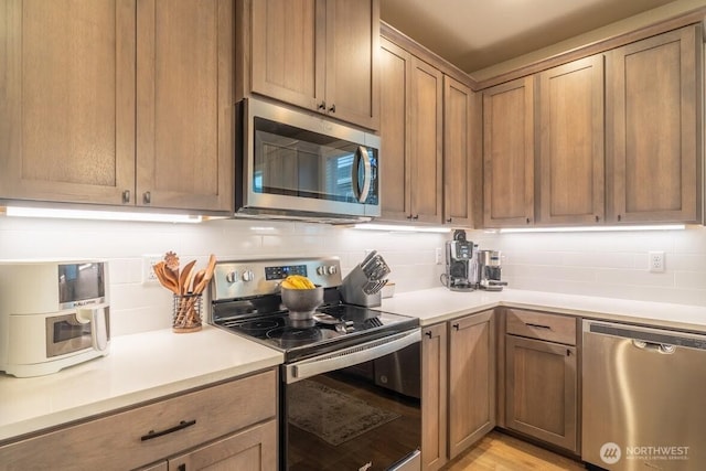 kitchen featuring decorative backsplash, light countertops, and appliances with stainless steel finishes