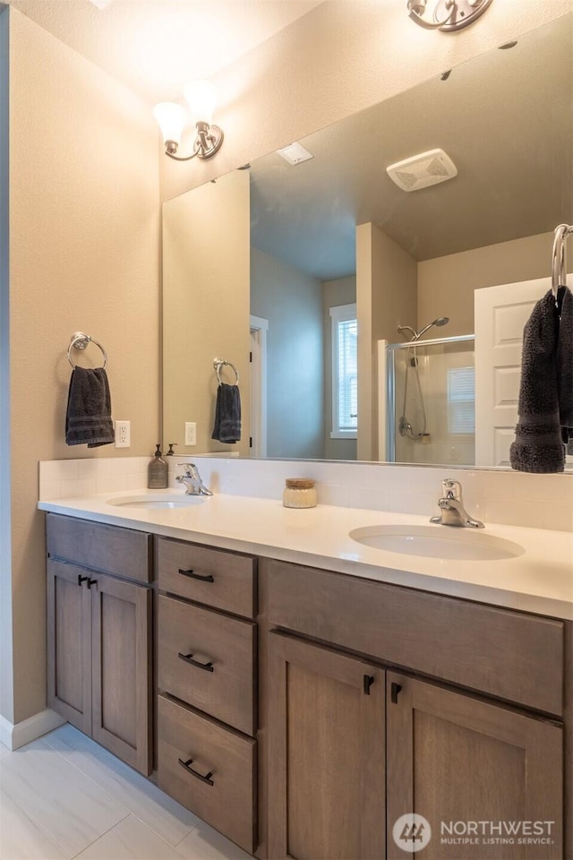 full bath with a sink, a stall shower, and double vanity