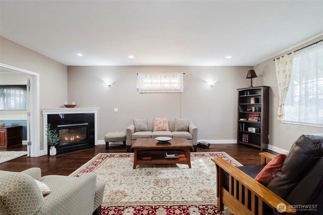 living room featuring dark wood finished floors, a tiled fireplace, and baseboards