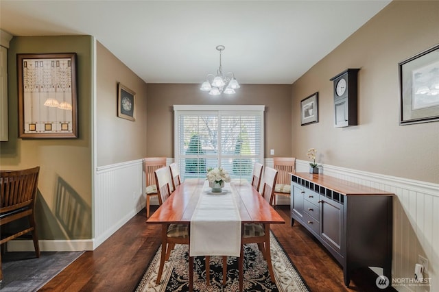 dining area featuring dark wood-style floors, a chandelier, and wainscoting