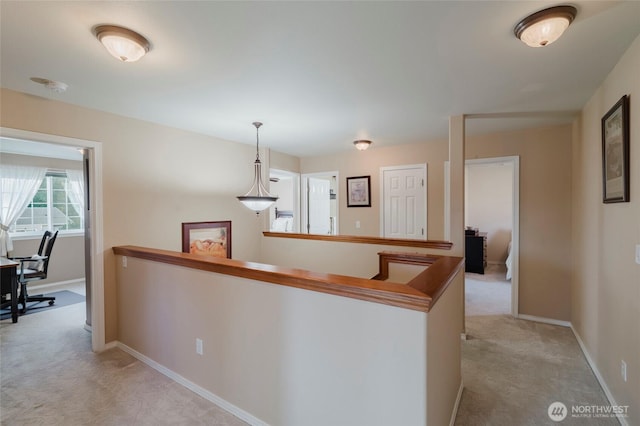 corridor featuring an upstairs landing, light colored carpet, and baseboards