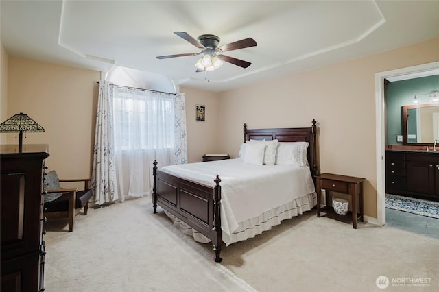 bedroom featuring baseboards, light colored carpet, a ceiling fan, and connected bathroom