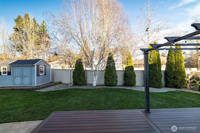 view of yard featuring a shed, a wooden deck, a fenced backyard, an outbuilding, and a pergola