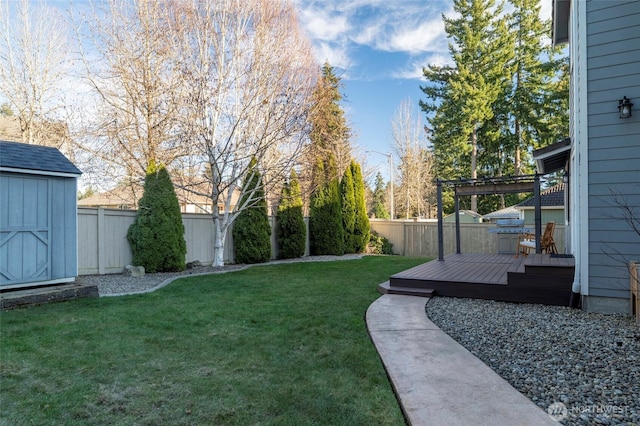 view of yard with a storage shed, an outbuilding, a fenced backyard, and a wooden deck