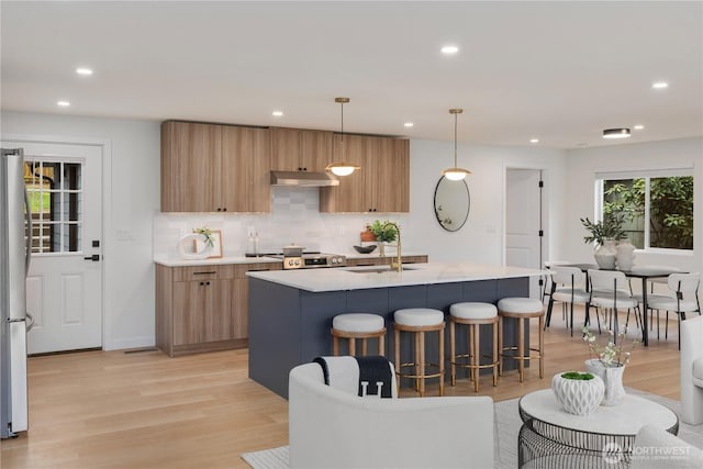 kitchen featuring under cabinet range hood, modern cabinets, light countertops, and a sink