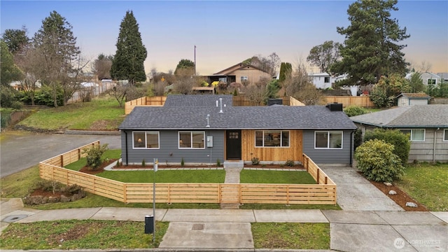 single story home featuring a fenced front yard, driveway, a shingled roof, and a yard