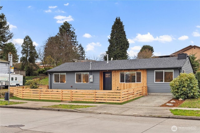 ranch-style home with a fenced front yard and a shingled roof