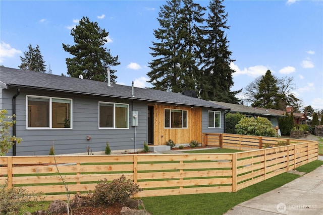 single story home with a shingled roof, a chimney, and fence