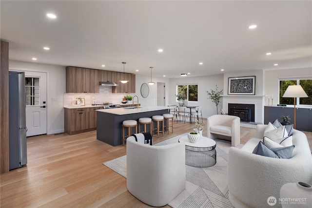 living room featuring a fireplace, recessed lighting, and light wood-style floors