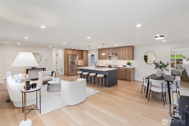 living room with visible vents, recessed lighting, light wood-style floors, and baseboards