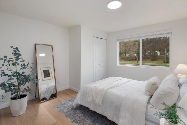 bedroom with a closet, baseboards, and light wood-style floors