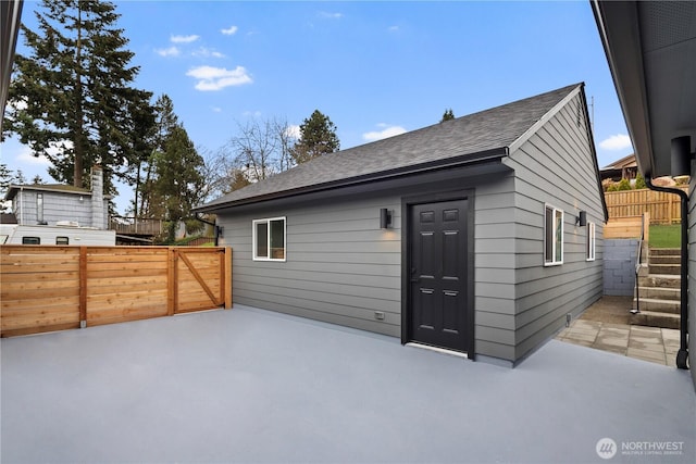 back of house with a patio area, fence, and roof with shingles