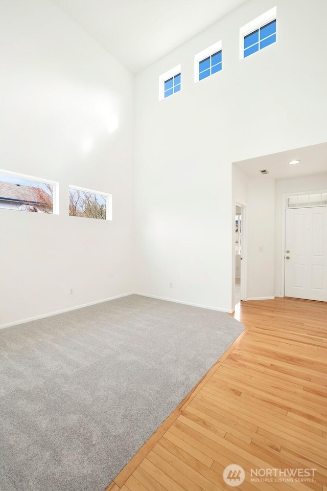 unfurnished living room featuring baseboards, a high ceiling, and wood finished floors