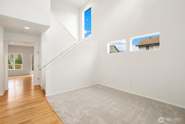 interior space featuring baseboards, wood finished floors, and a towering ceiling