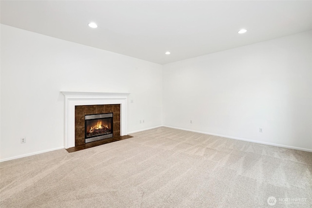 unfurnished living room featuring recessed lighting, light colored carpet, and a fireplace